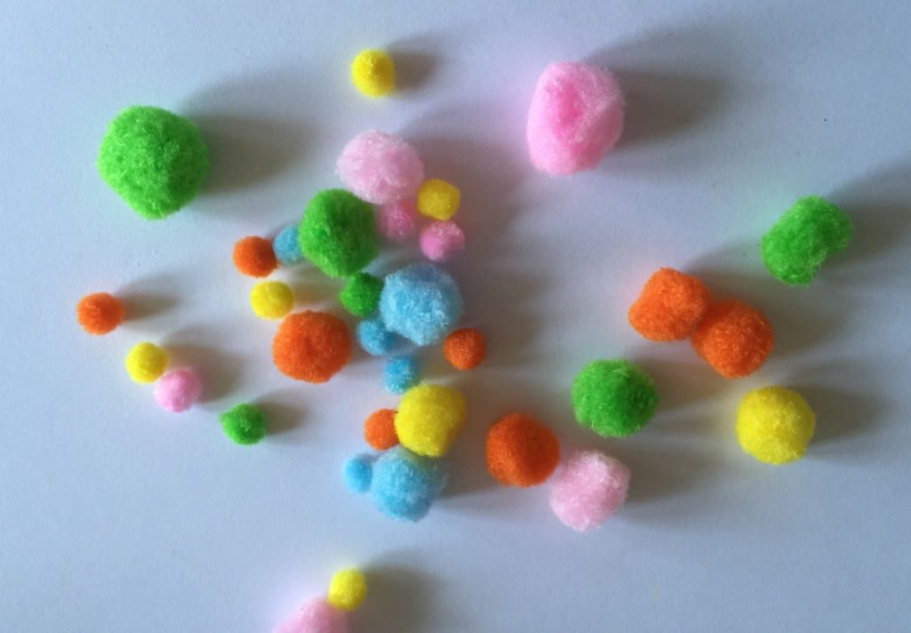 bag of different sizes of pom poms