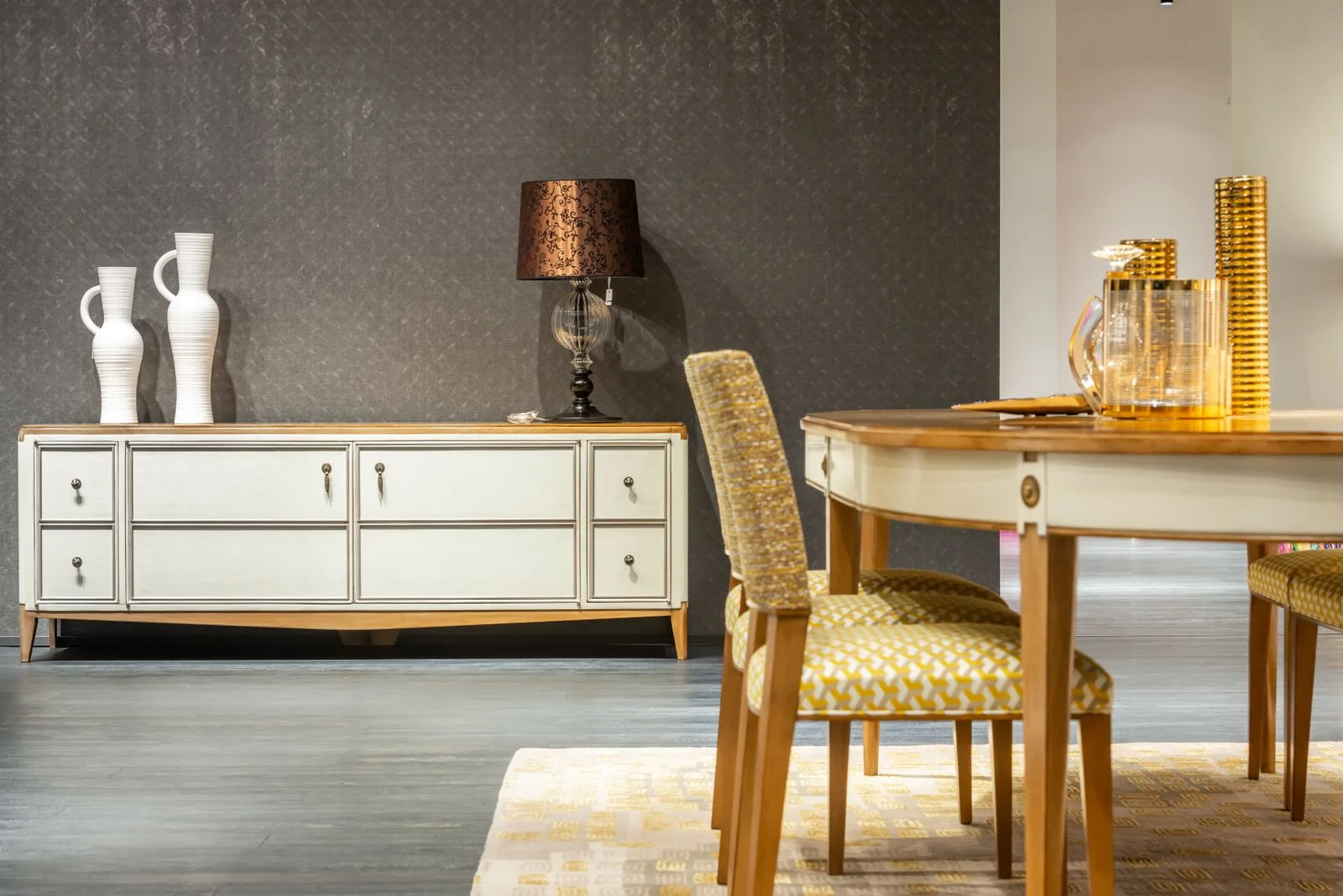 A dining area with an upholstered chair, round table and sideboard