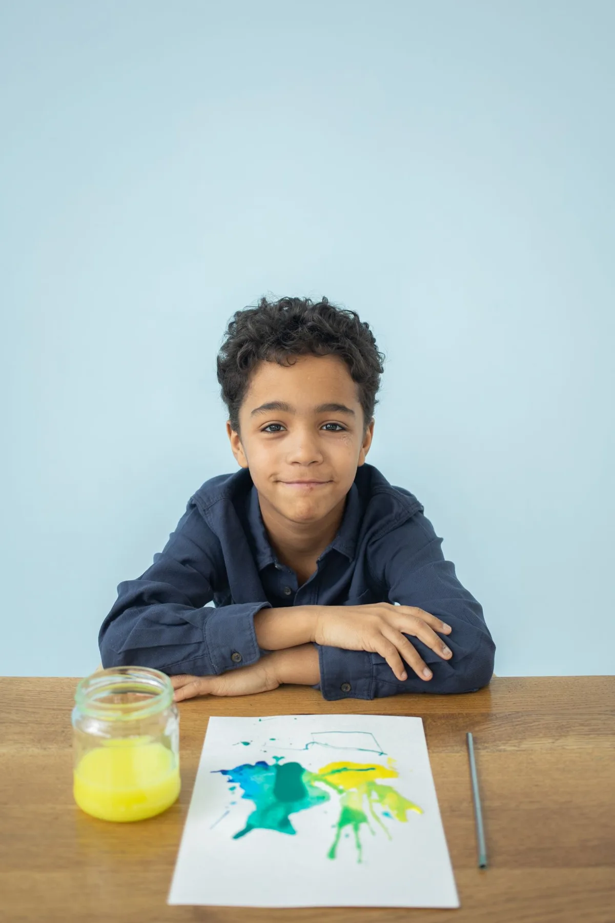 A child seated at a table with a painted picture