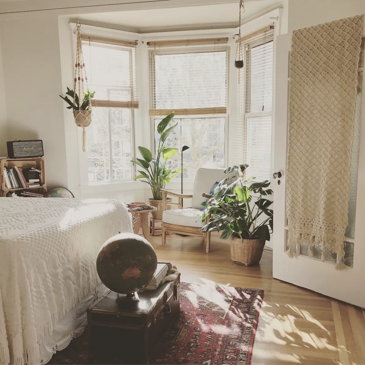 A bright room corner with a chair, curtains and a large round mirror