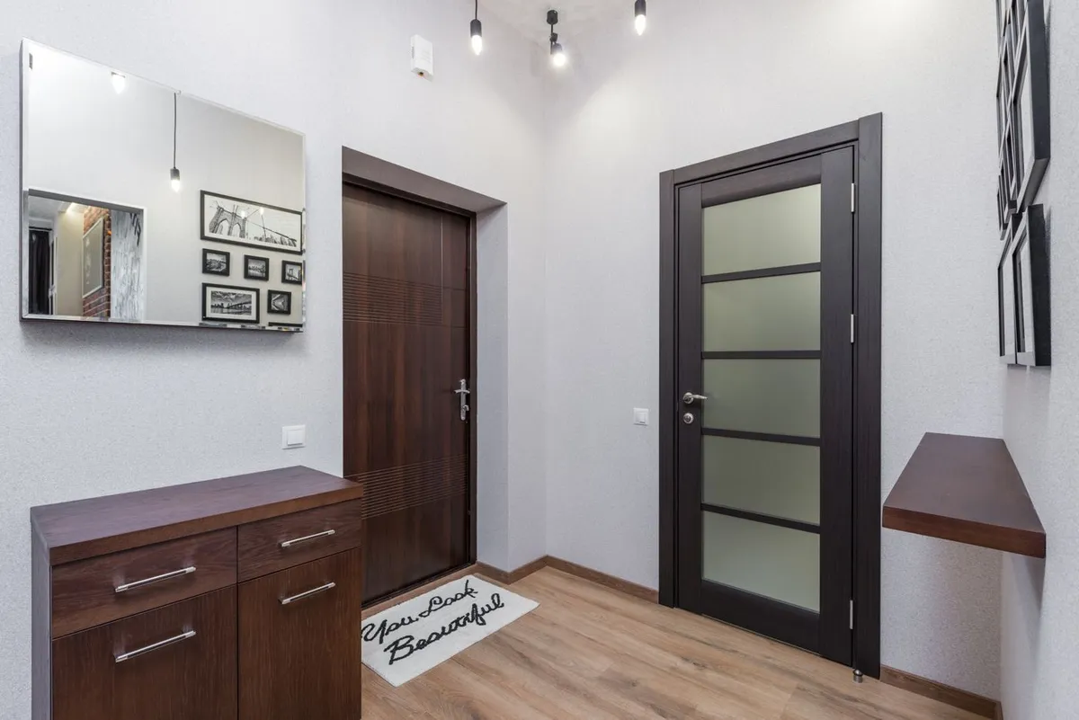 An interior entryway with a mirror, framed artwork and dark wood details.