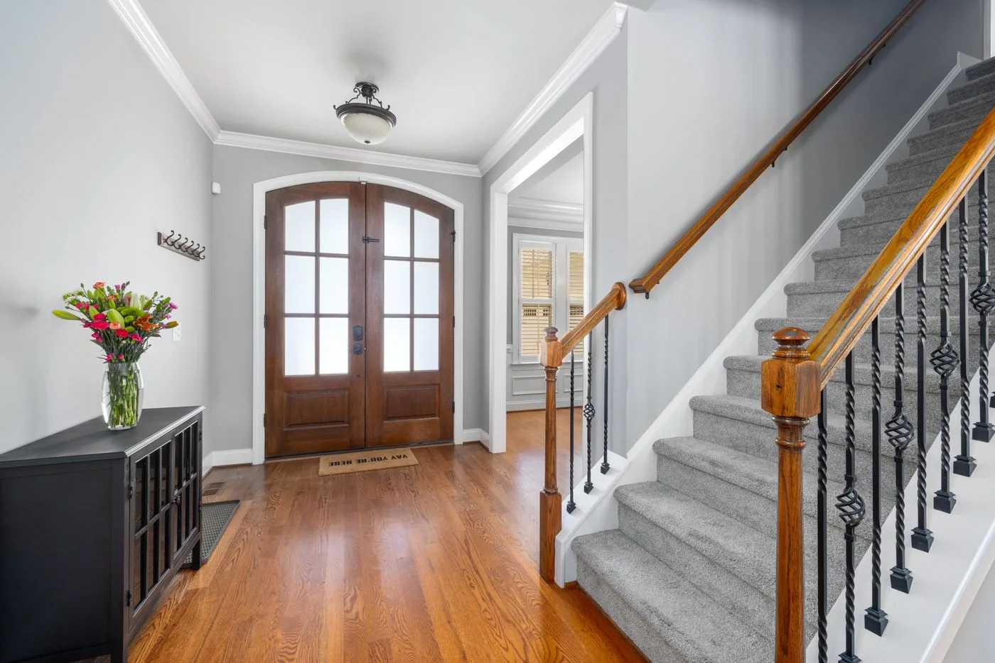 A foyer with wooden front door, staircase and dark console