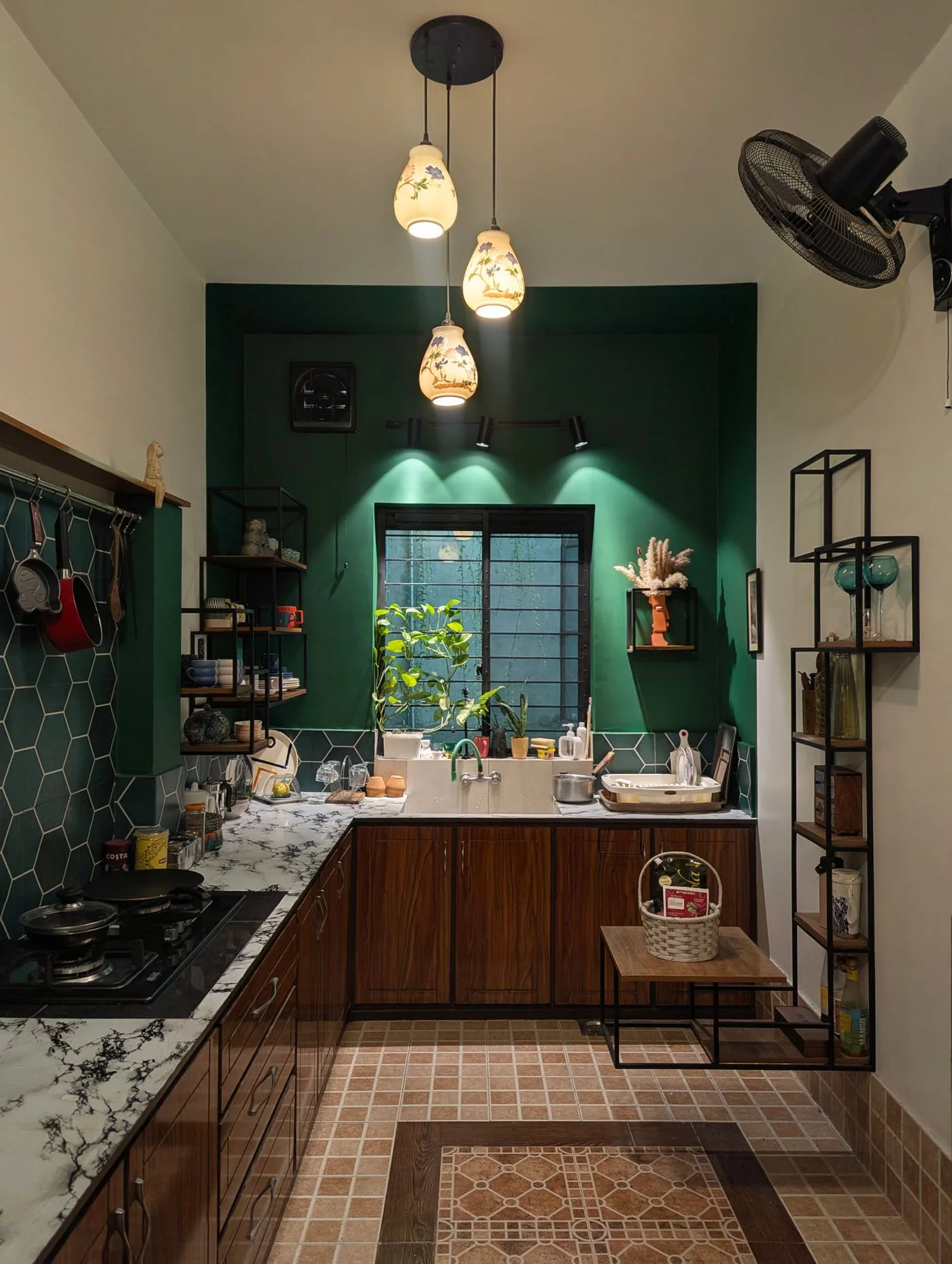 A kitchen with a dark green wall, window and open shelves