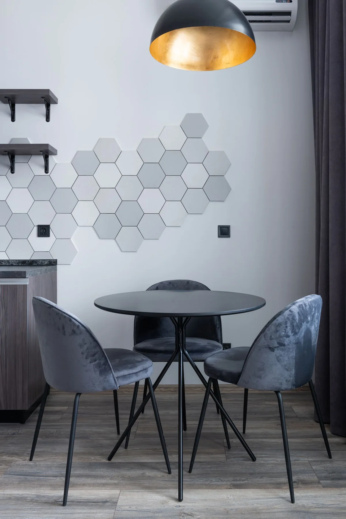 A round dining table and upholstered chairs against a patterned wall