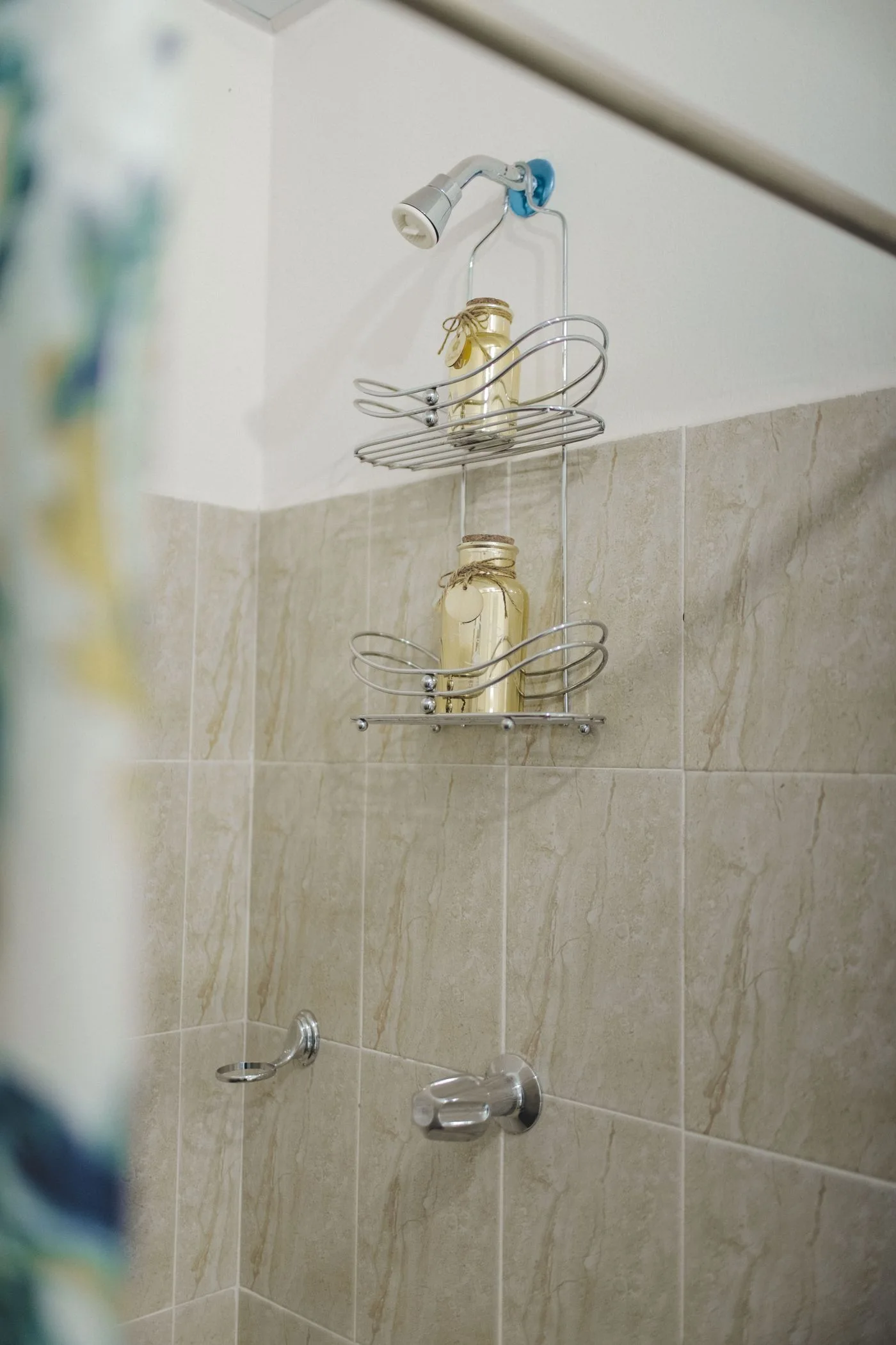 A wire shower shelf holding containers against tiled walls